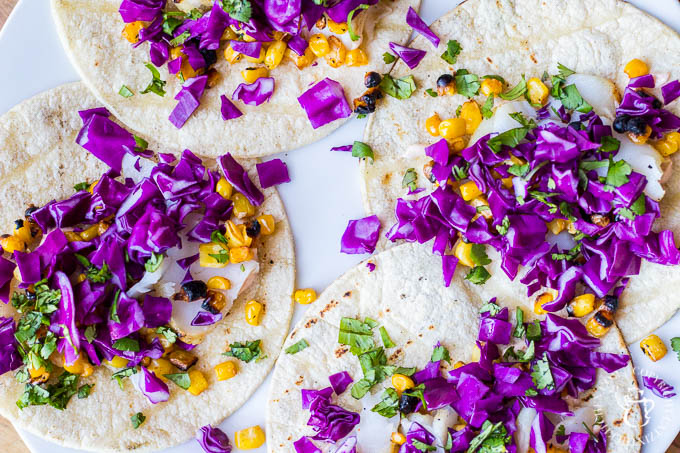Top the tortillas conservatively with the flaked fish, and then add corn, red cabbage, cilantro and garnish with lime wedges. That's it - time to eat!
